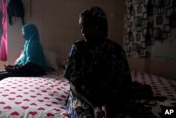 Nagad Daoud Abdallah, right, and Majdah Ishag, both from Sudan, sit on a bed in Ishag's room at a hotel turned into a shelter for refugees in Batam, an island in northwestern Indonesia, May 16, 2024.